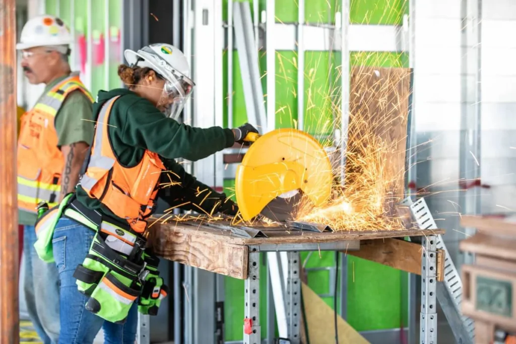 female construction worker using a saw to cut sheet of metal